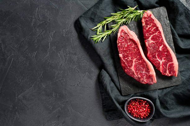 istock sirloin a raw beef steak. Black background, top view. 1142895325