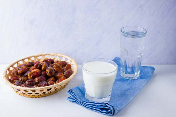 getrocknete datteln und milch auf weißem hintergrund. der heilige monat ramadan, konzept. gerechter muslimischer lebensstil. hunger. termine in holzkorb und wasser. vegetarisches essen. kopierplatz - righteous stock-fotos und bilder