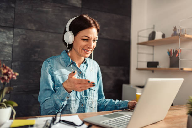 Business woman doing video call at office Business woman wearing white headphones doing video call at work online tutors stock pictures, royalty-free photos & images