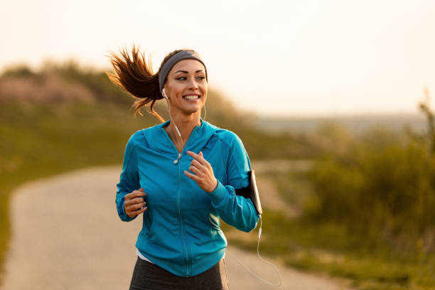Happy female runner jogging in the morning in nature. Dedicated athletic woman running in nature and dawn. sports stock pictures, royalty-free photos & images