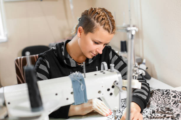 istock Seamstress sewing at machine, portrait. Female tailor stitching material at workplace. Preparing fabric for clothes making. Tailoring, garment industry, designer workshop concept 1142901236