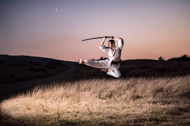 Martial artist performing a high kick with samurai sword.