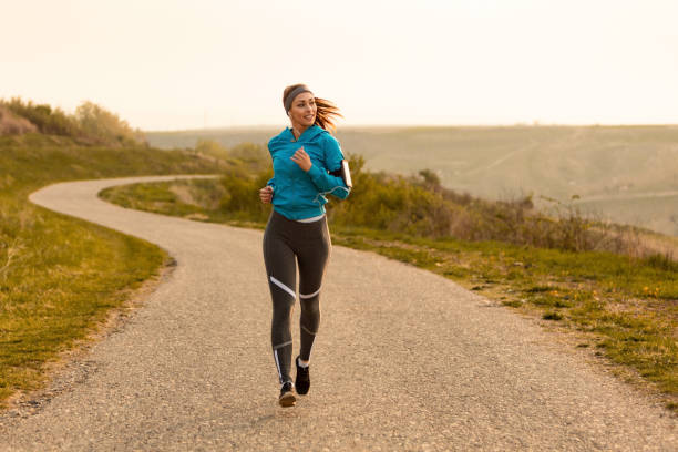 mujer atlética motivado a partir de su día con la mañana correr en la naturaleza. - corredora de footing fotografías e imágenes de stock