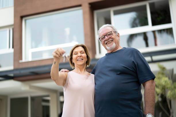 mature couple holding the keys from their new house - garden key imagens e fotografias de stock