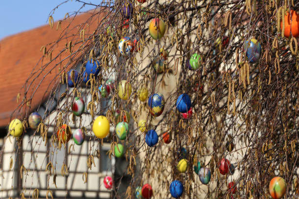 Basket with Easter eggs on a green lawn near a pair of rubber boots, watering can