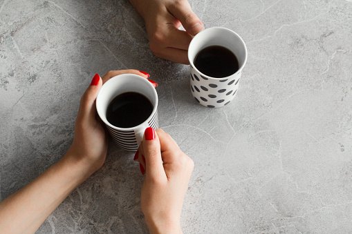 Person hands drinking coffee cup on gray background