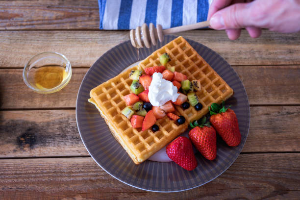 istock Honey poured onto fresh waffles with fruits 1142915546