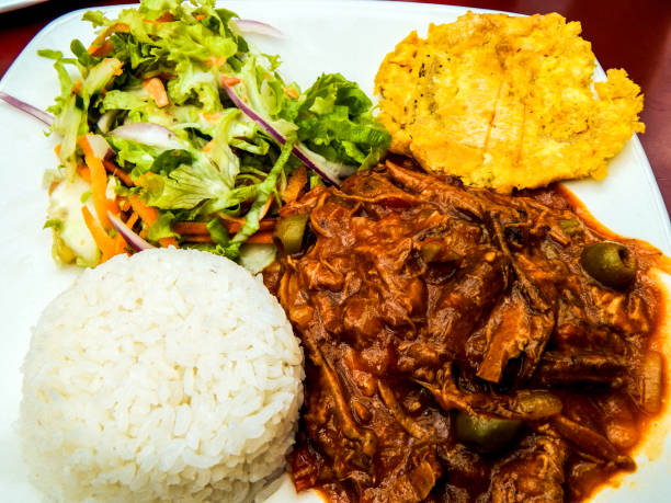 istock Ropa vieja dish with rice and vegetables in a white plate over a red table 1142921468