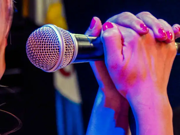 Singer holding the microphone with two hands with nail polish