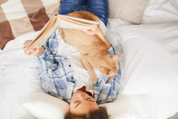 istock Woman Reading Book with Cat 1142921632