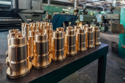 New brass threaded bushings on table in factory.