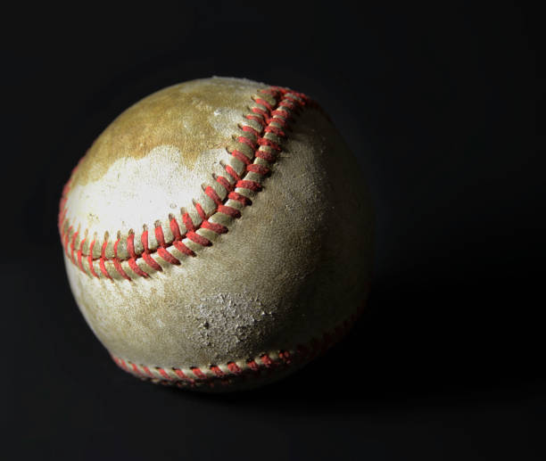 istock Old used baseball against black background with dramatic lighting. 1142925428