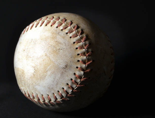 istock Old softball with scuff marks on black background with dramatic lighting. 1142925446