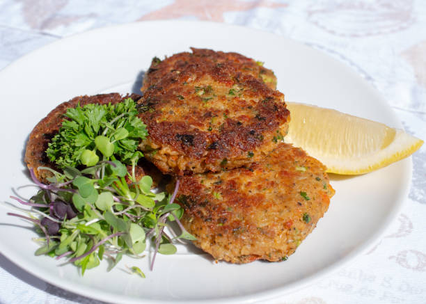 istock Fresh crab cakes served on a white plate with lemon and salad. 1142928103