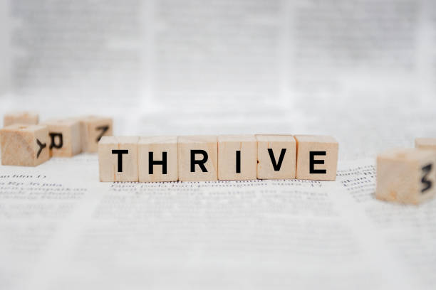 istock Thrive Word Written In Wooden Cube - Newspaper 1142950563