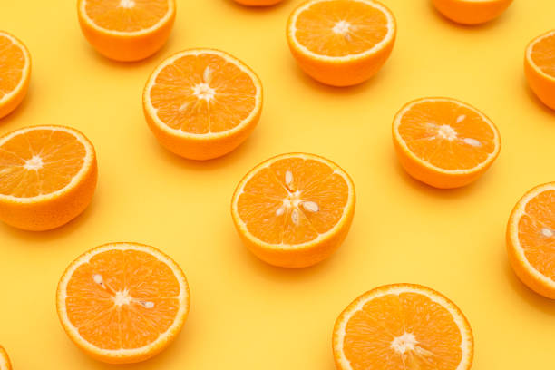 istock Orange juicy oranges split in half on yellow 1142953143