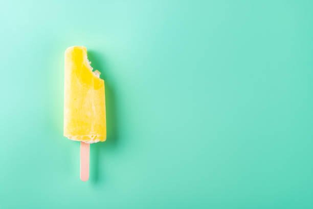 istock yellow popsicle with a bite on a light blue background 1142959168