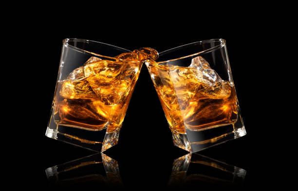 glasses of whiskey making toast glasses of whiskey making toast with splashes on black background whiskey stock pictures, royalty-free photos & images