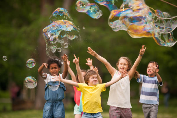 attraper des bulles arc-en-ciel dans le parc! - bubble wand child outdoors bubble photos et images de collection