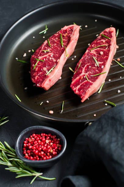 istock Marble beef steak black Angus on the grill pan. Black background, top view. 1142971592