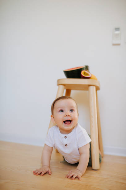 istock An infant baby is crawling from under the stool with fruits on it 1142974093