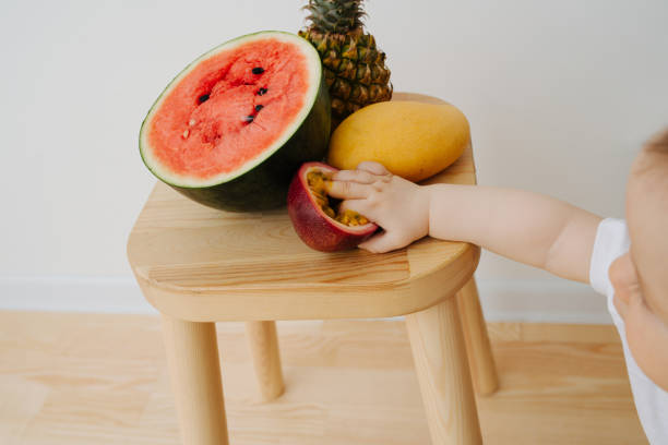 istock An infant baby and fruits on a stool 1142974126