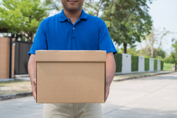 istock Blue Delivery man holding parcel cardboard box. 1142974302