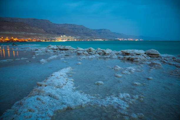 Close up of natural salt crystals, texture of salt. Small waves touching against salted rock shore at the Dead Sea coast, Jordan.