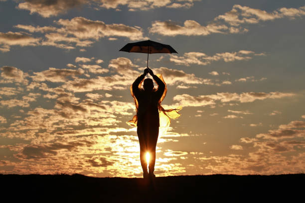 istock Silhouette girl with umbrella on sunset background 1142979656