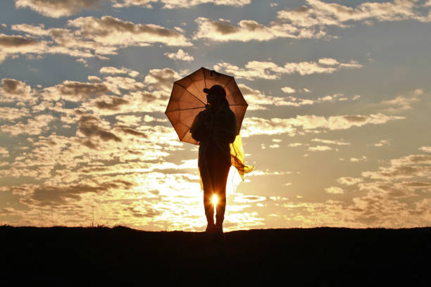 istock Silhouette girl with umbrella on sunset background 1142979681