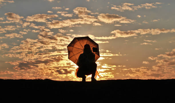 istock Silhouette girl with umbrella on sunset background 1142980353