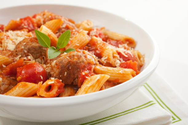 Pasta with Meatballs and Marinara A bowl of meatballs with penne pasta, marinara sauce, parmesan cheese and garnished with basil. penne meatballs stock pictures, royalty-free photos & images