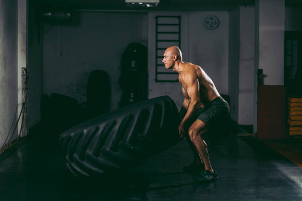 istock Hardcore workout- shirtless muscular bodybuilder doing flipping tire exercise 1142983893