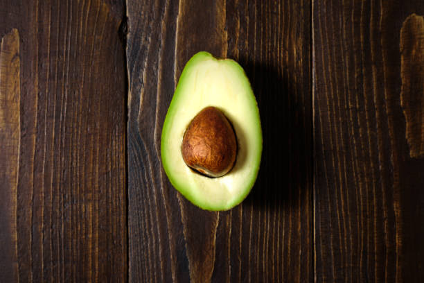 istock Avocado half on wooden background 1142989636