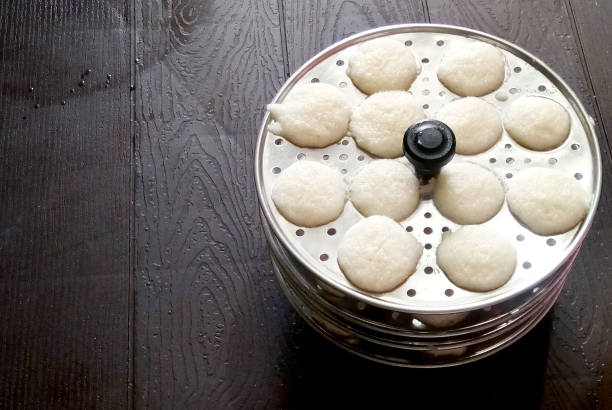 Making rava idli or rava idly is a popular South Indian breakfast dish. cooking Idly in a traditional pot in Kerala India Kitchen. Steamed food. dish made from semolina dushera diwali