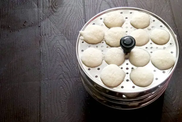 Photo of Making rava idli or rava idly is a popular South Indian breakfast dish. cooking Idly in a traditional pot in Kerala India Kitchen. Steamed food. dish made from semolina dushera diwali