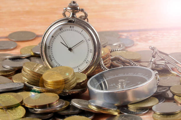 istock Close-Up Of Coins With Pocket Watch And Compass On Table 1142993585