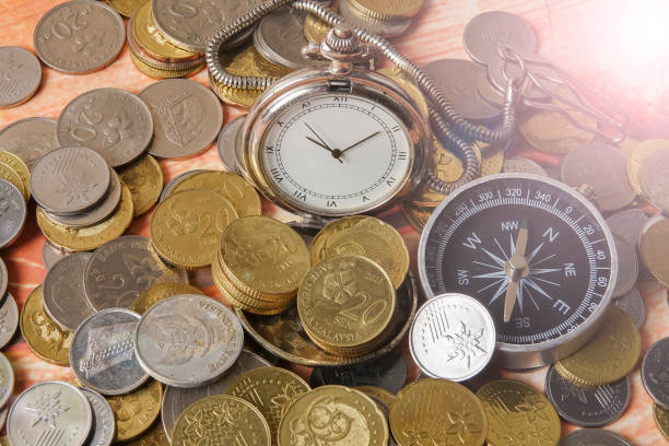 istock Close-Up Of Coins With Pocket Watch And Compass On Table 1142993621