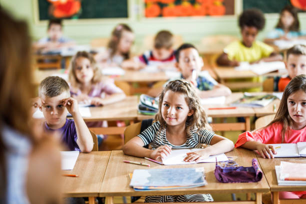 istock Group of elementary students listening on a class in the classroom. 1142997271