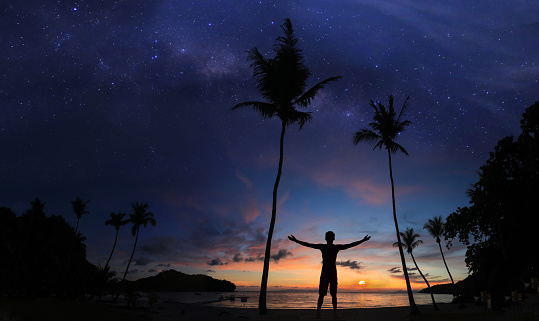 Man standing on the coconut beach with a million stars and sunrise early morning.Panoramic landscape