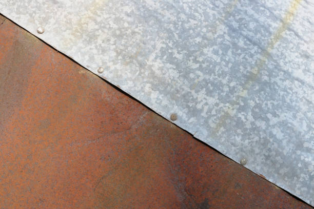 Sheets of rusty red and galvanized  silver steel are riveted together