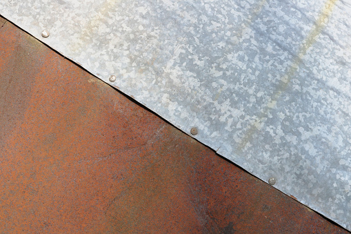 Sheets of rusty red and galvanized  silver steel are riveted together. Outdoor macro background