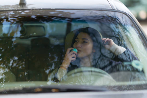 istock Woman behind the wheel sniffing blue bottle 1143000157