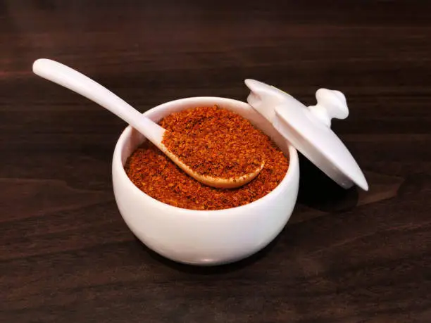 Photo of Shichimi togarashi,Cayenne pepper in a white cup, preparing to put in Ramen noodles or gydon. Popular Japanese seasoning.