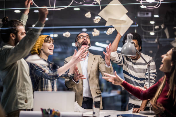 istock Team of cheerful entrepreneurs having fun while throwing papers in the office. 1143001188