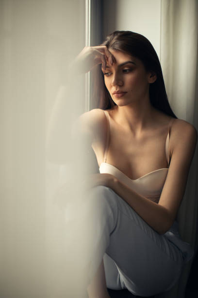 istock Young sensual woman sitting on window at home 1143003412