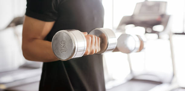 close up young asian man lifting metal dumbbell for playing bicep curl pattern at gym in the morning  , healthy lifestyle concept - body care asian ethnicity body building toughness imagens e fotografias de stock