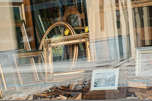Closeup view of window showcase antique shop with old wooden frames for paintings and mirrors