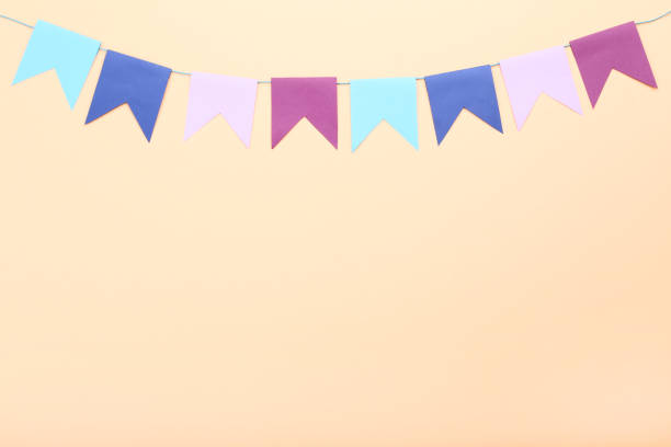 istock Colorful paper flags hanging on beige background 1143009056