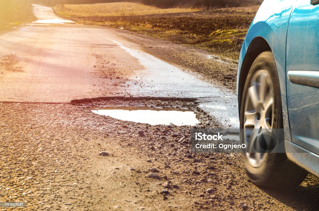 Car and winter pothole on open road Pot Hole Stock Photo